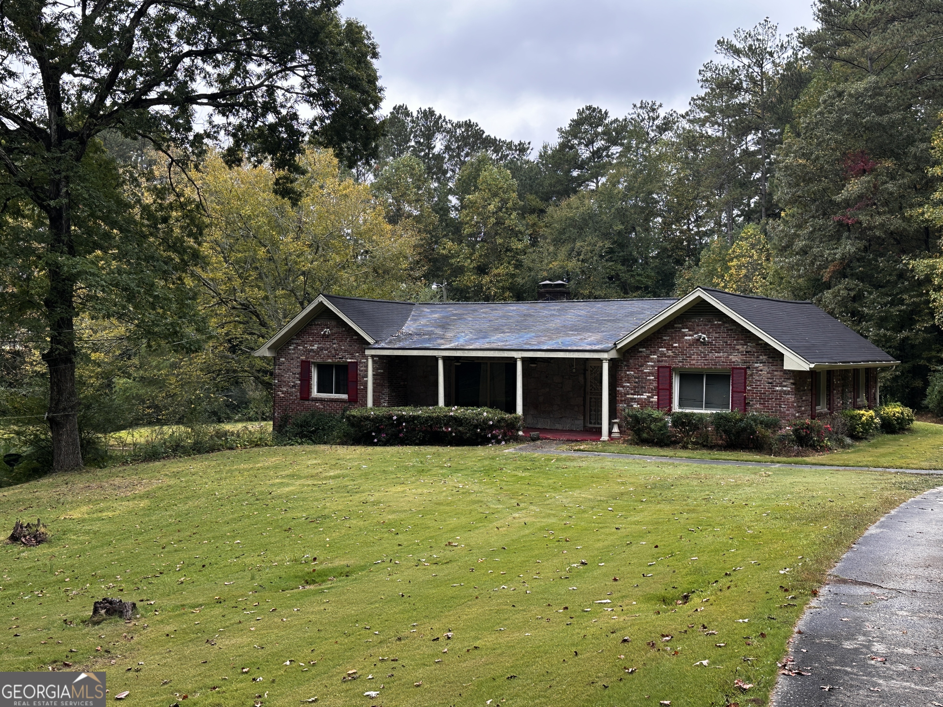 a brick house with a big yard and large trees