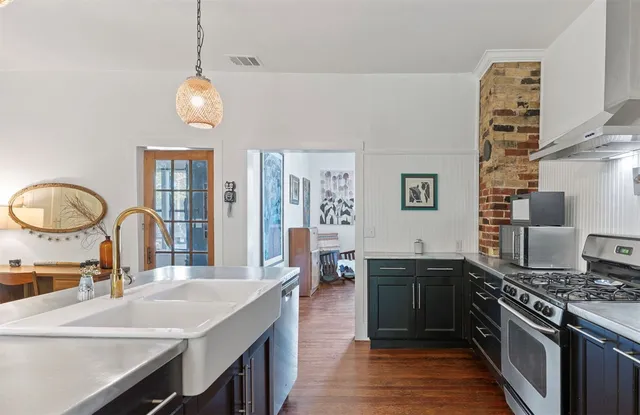 a large kitchen with stainless steel appliances a stove oven and a dining table with wooden floor