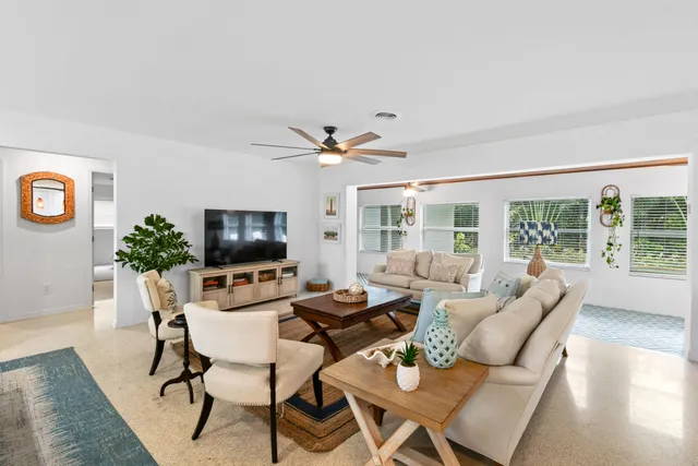a living room with furniture floor to ceiling window and a flat screen tv