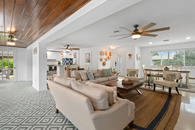 a living room with furniture kitchen view and a large window