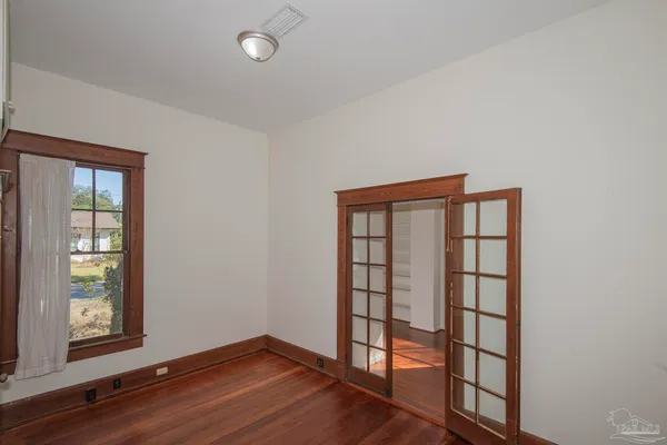 an empty room with wooden floor and windows