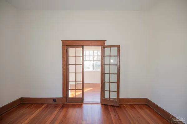 an empty room with wooden floor and windows