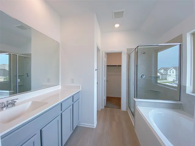 a spacious bathroom with a bathtub shower sink mirror and toilet