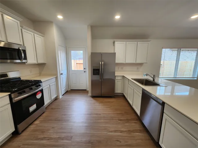 a kitchen with granite countertop a refrigerator stove top oven and sink