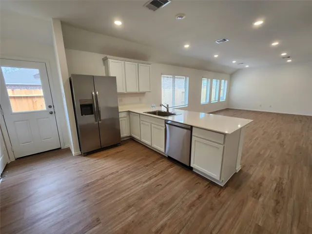 a kitchen with stainless steel appliances granite countertop a sink a refrigerator a stove a microwave and island with wooden floor