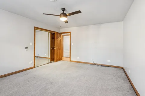 an empty room with windows and chandelier fan