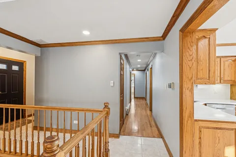 a view of hallway with wooden floor and a bathroom