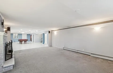 an empty room with wooden floor pool table and windows