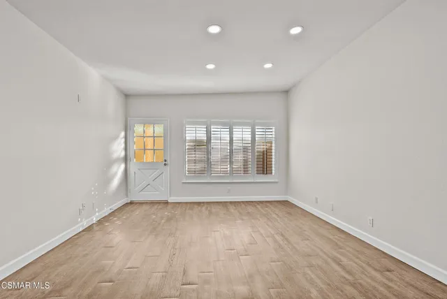 an empty room with wooden floor and windows