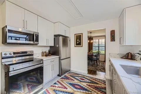 a kitchen with stainless steel appliances a stove a sink a refrigerator cabinets and a window