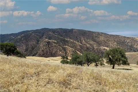 a view of a dry yard with mountains in the background