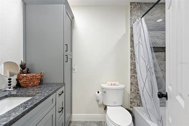 a bathroom with a granite countertop toilet and a sink