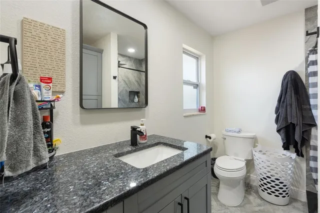a bathroom with a granite countertop toilet sink and mirror