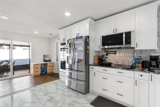 a kitchen with granite countertop a refrigerator stove and microwave