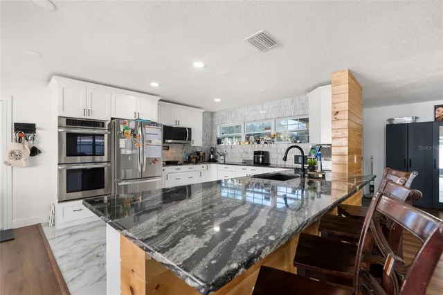 a kitchen with stainless steel appliances granite countertop a sink refrigerator stove and microwave