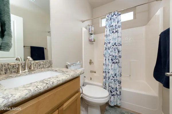 a bathroom with a granite countertop sink a mirror a toilet and shower