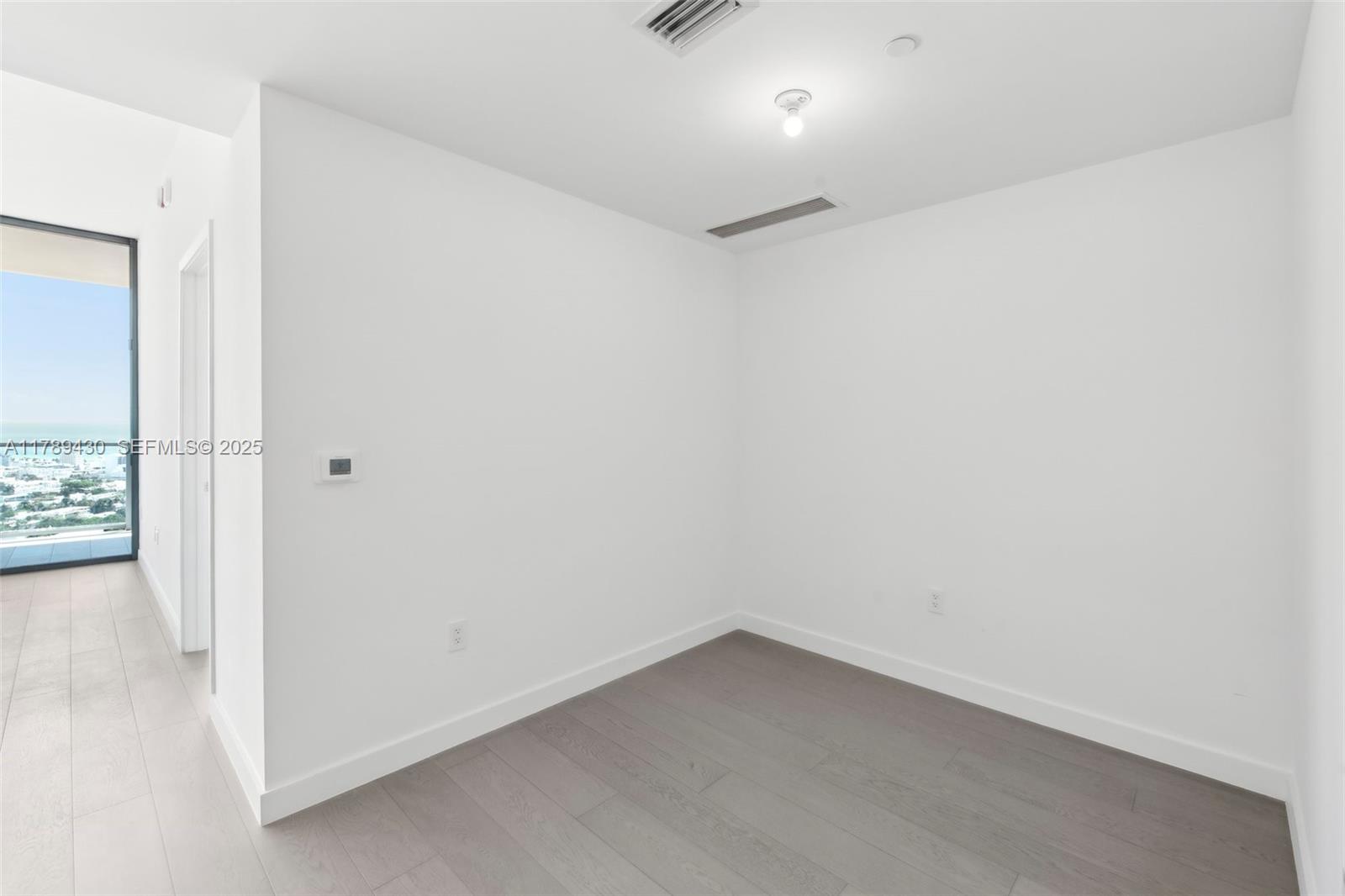 500 Alton Road, Unit 3004 Miami Beach, FL 33139 - Photo 11 of 31 an empty room with wooden floor and windows