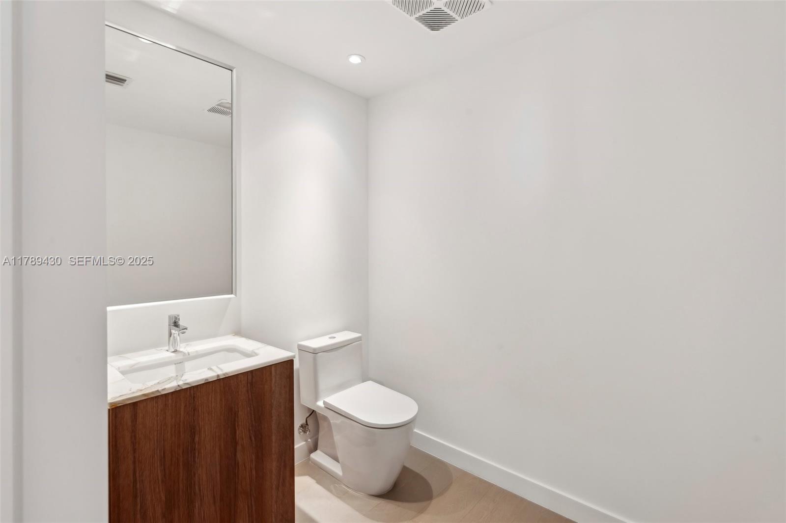 500 Alton Road, Unit 3004 Miami Beach, FL 33139 - Photo 21 of 31 a bathroom with a granite countertop toilet and a sink