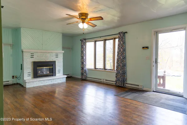 an empty room with wooden floor a fireplace and windows