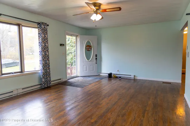 an empty room with wooden floor and windows