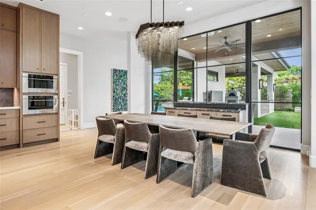 a dining room with stainless steel appliances granite countertop a table chairs and a large window
