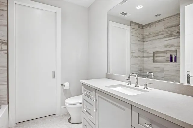 a bathroom with a granite countertop sink a toilet and a mirror