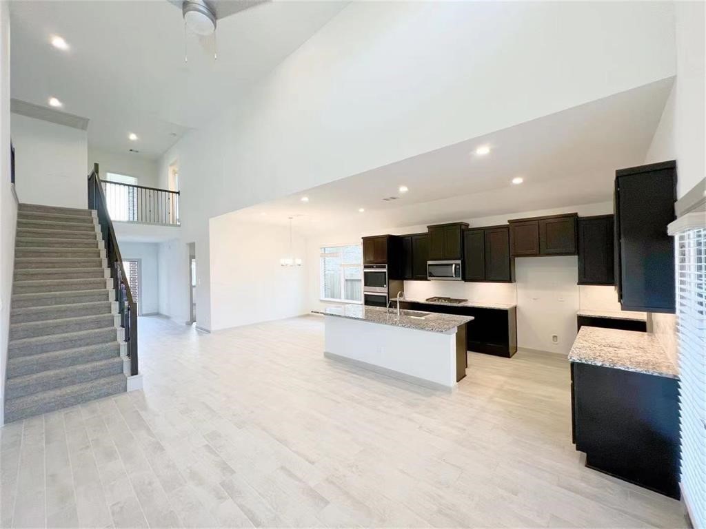 28310 Hazel Trail Katy, TX 77494 - Photo 8 of 26 a view of kitchen with microwave stove refrigerator and couches with wooden floor