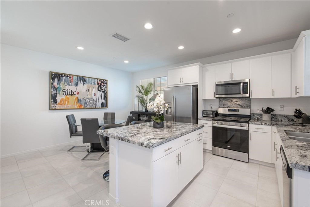 8474 Explorer Street Chino, CA 91708 - Photo 5 of 36 a kitchen with a stove a sink a microwave a dining table and chairs