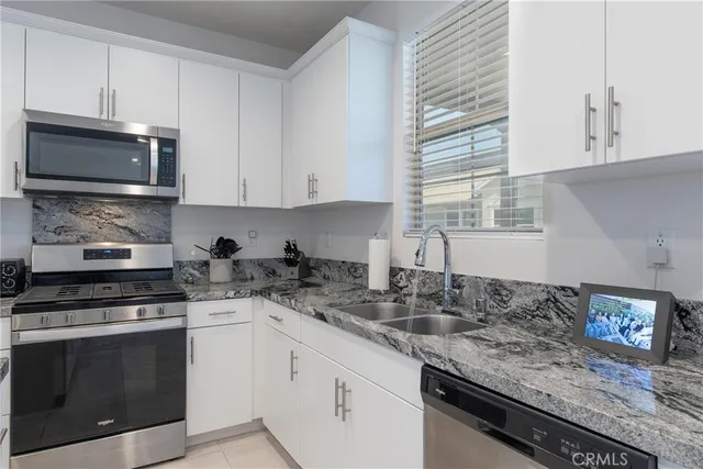 a kitchen with granite countertop a sink stainless steel appliances and cabinets