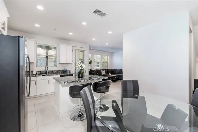 a kitchen with a sink a stove a refrigerator cabinets and a dining table