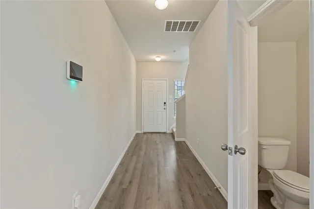 a view of a hallway with wooden floor and a bathroom