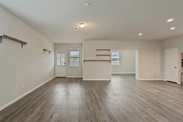 a view of an empty room with a window and wooden floor