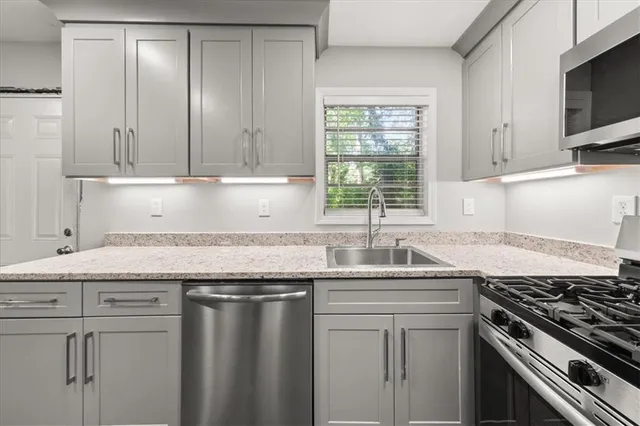 a kitchen with granite countertop a sink stove and cabinets