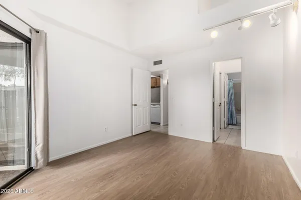 a view of an empty room with wooden floor and a window