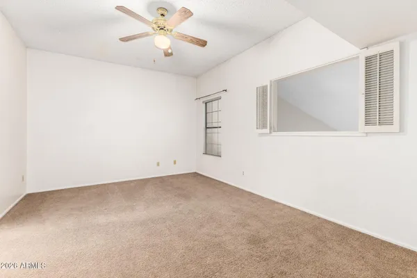 an empty room with a window and a ceiling fan