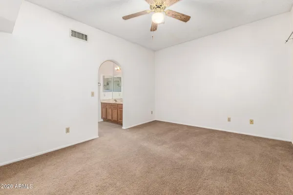 an empty room with a chandelier fan and windows