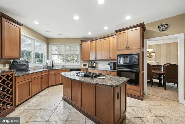 a kitchen with granite countertop kitchen island stainless steel appliances a refrigerator a stove a sink cabinets and a dining table