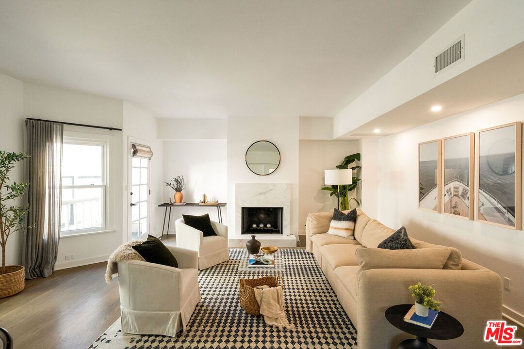 a living room with furniture a fireplace a rug and a large window
