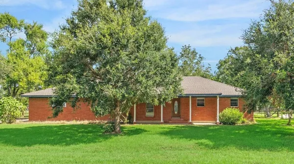 a front view of a house with a garden and trees