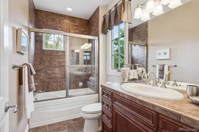 a bathroom with a granite countertop sink a toilet a mirror and bathtub