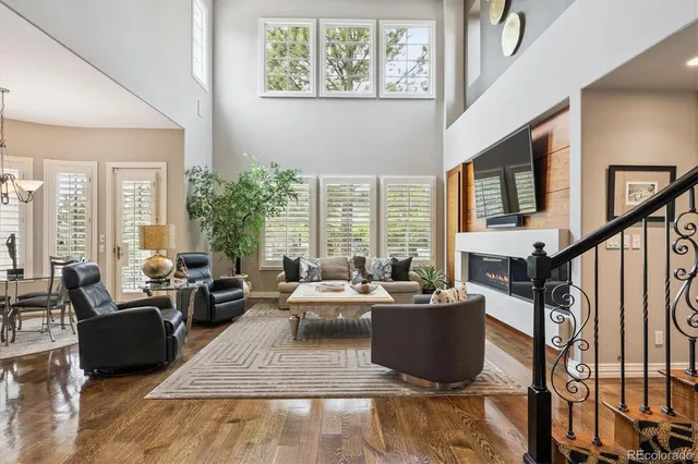 a living room with furniture potted plant floor to ceiling windows and a flat screen tv