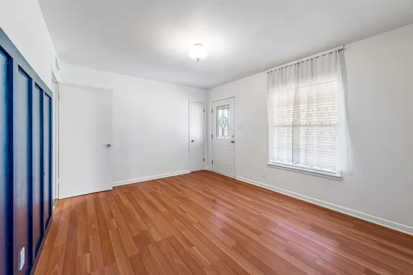 an empty room with wooden floor fan and windows