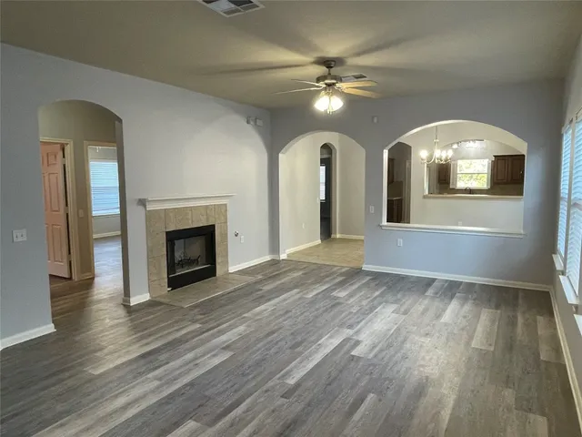 a view of an empty room with wooden floor fireplace and a window