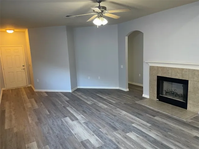 an empty room with wooden floor a fireplace a ceiling fan and wooden floor