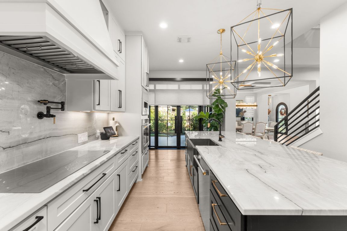 8 Hightrail Way The Hills, TX 78738 - Photo 5 of 15 a large kitchen with kitchen island a large counter space a sink appliances and cabinets