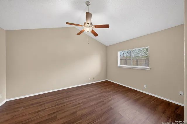 a view of a room with wooden floor ceiling fan and window
