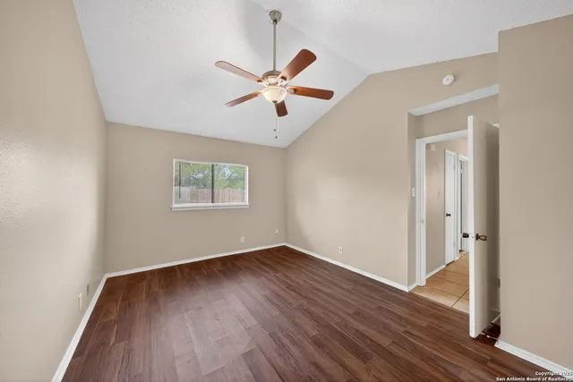 an empty room with wooden floor ceiling fan and windows