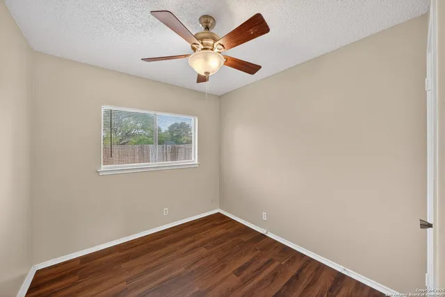 an empty room with wooden floor and ceiling fan