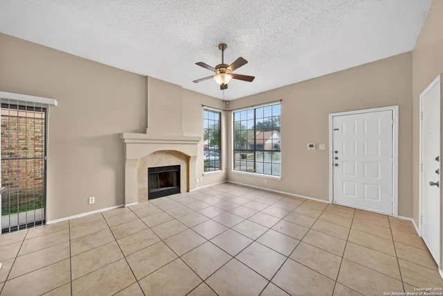 a view of a livingroom with a fireplace chandelier fan and windows