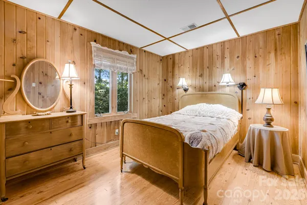 a bedroom with a bed a mirror on dresser and a chandelier